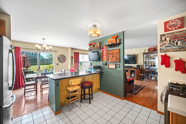 5613 W Von Ave, Monee, IL 60449 - kitchen featuring a chandelier, a peninsula, appliances with stainless steel finishes, light tile patterned flooring, and a breakfast bar