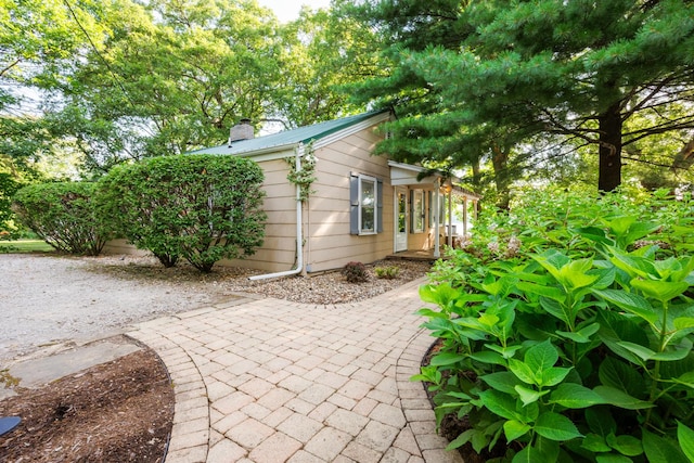 24503 Iroquois Ln, Hudson, IL 61748 - view of property exterior featuring a chimney, a patio, and a metal roof