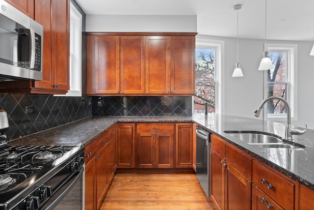2864 N Riverwalk Dr, Chicago, IL 60618 - kitchen featuring appliances with stainless steel finishes, light wood-type flooring, dark stone countertops, backsplash, and pendant lighting