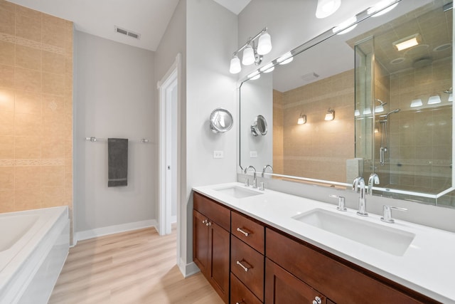 2864 N Riverwalk Dr, Chicago, IL 60618 - bathroom with double vanity, a shower stall, wood finished floors, and a bath
