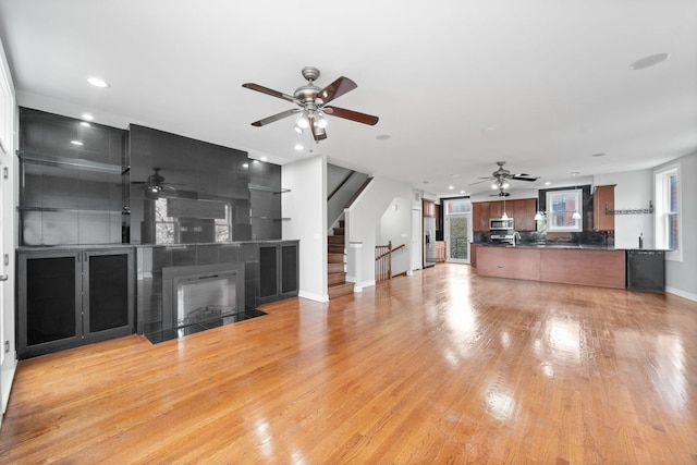 2864 N Riverwalk Dr, Chicago, IL 60618 - unfurnished living room featuring a ceiling fan, recessed lighting, stairway, light wood-style flooring, and a tiled fireplace