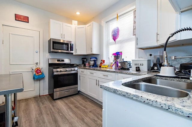 5523 W Huron St, Chicago, IL 60644 - kitchen with stainless steel appliances, white cabinetry, wood finished floors, recessed lighting, and light stone countertops