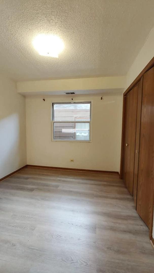 222 W 26th St Unit 202, Chicago, IL 60616 - unfurnished bedroom featuring a textured ceiling, a closet, and light wood finished floors