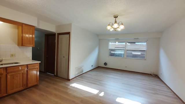 222 W 26th St Unit 202, Chicago, IL 60616 - unfurnished dining area with light wood-style floors, a chandelier, and a textured ceiling