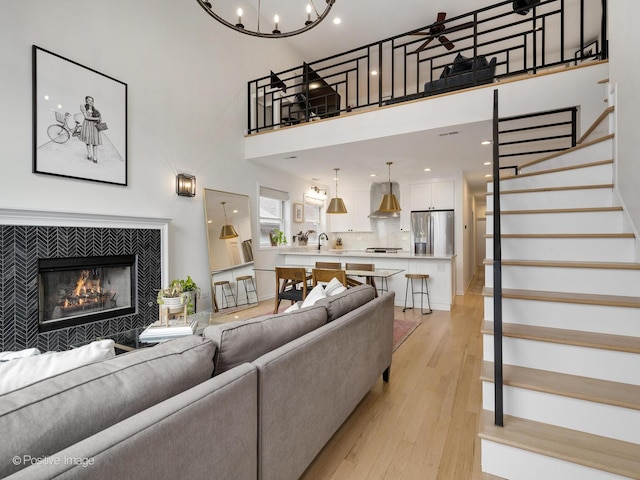 2026 W Pierce Ave Unit 7, Chicago, IL 60622 - living room with stairs, light wood-style flooring, a tile fireplace, a towering ceiling, and a ceiling fan