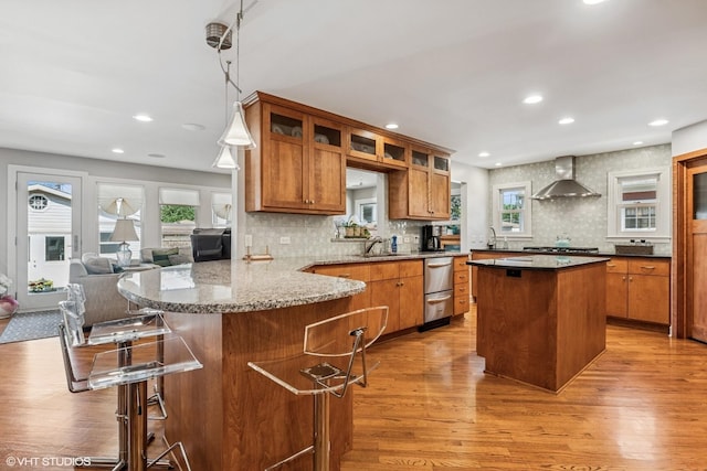 1820 N 75th Ct, Elmwood Park, IL 60707 - kitchen featuring wall chimney exhaust hood, light wood-style floors, brown cabinetry, appliances with stainless steel finishes, and plenty of natural light