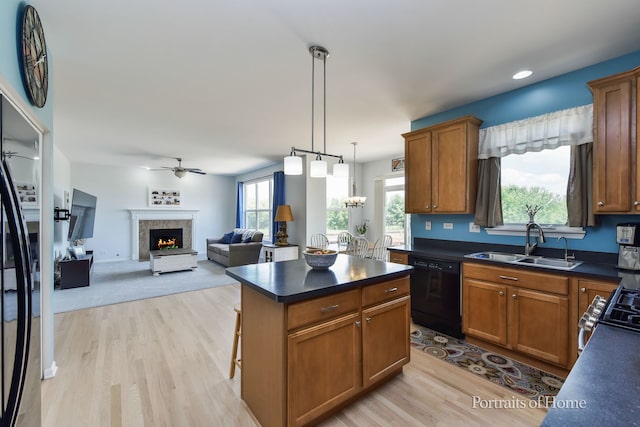239 Morgan Valley Dr, Oswego, IL 60543 - kitchen with dishwasher, dark countertops, light wood-style floors, a ceiling fan, and a lit fireplace