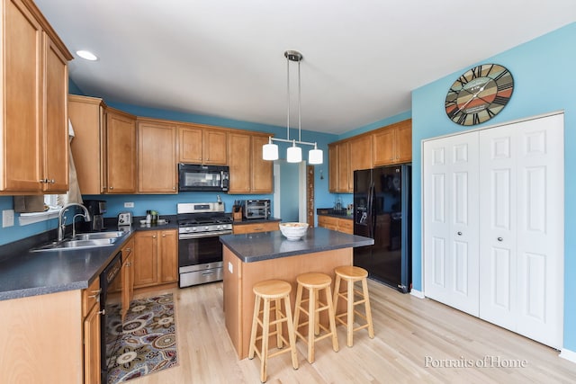 239 Morgan Valley Dr, Oswego, IL 60543 - kitchen with black appliances, light wood-style flooring, dark countertops, a kitchen island, and a kitchen bar