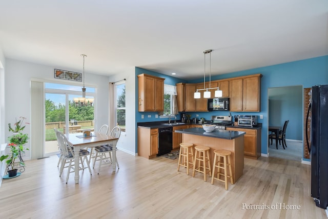 239 Morgan Valley Dr, Oswego, IL 60543 - kitchen with black appliances, a chandelier, dark countertops, a kitchen island, and light wood-style floors