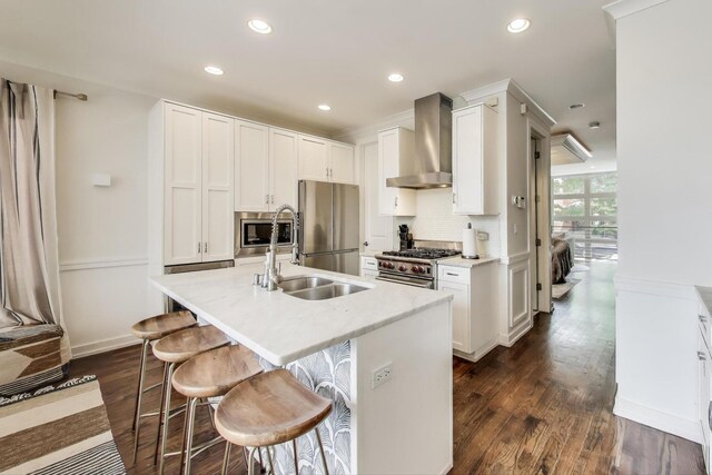 2423 W Erie St, Chicago, IL 60612 - kitchen with wall chimney exhaust hood, stainless steel appliances, dark wood-style floors, an island with sink, and recessed lighting