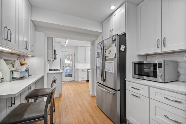 2837 W Coyle Ave, Chicago, IL 60645 - kitchen featuring stainless steel appliances, backsplash, light wood-style floors, white cabinetry, and recessed lighting