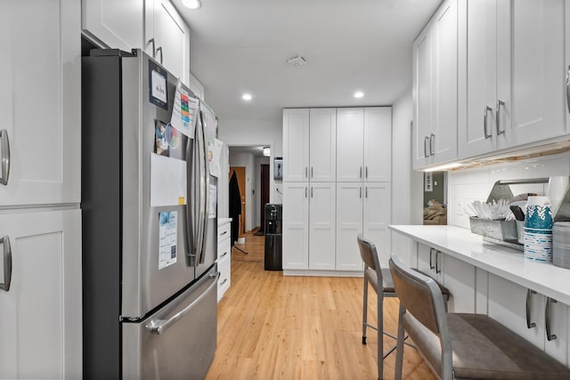 2837 W Coyle Ave, Chicago, IL 60645 - kitchen featuring stainless steel fridge with ice dispenser, light countertops, white cabinets, light wood-style flooring, and recessed lighting
