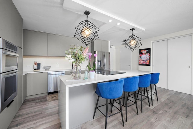 330 W Diversey Pkwy Unit 1606, Chicago, IL 60657 - kitchen with appliances with stainless steel finishes, gray cabinetry, modern cabinets, a breakfast bar, and light wood-style flooring