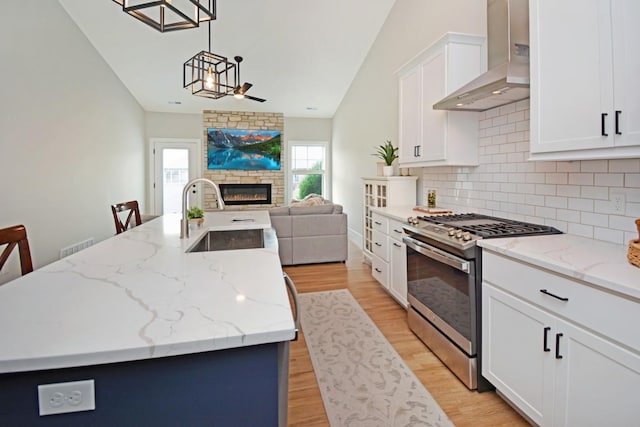 1723 Glenbridge Rd, Bloomington, IL 61704 - kitchen featuring stainless steel range with gas stovetop, wall chimney exhaust hood, open floor plan, a fireplace, and vaulted ceiling