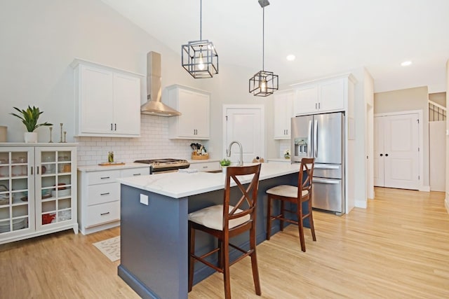 1723 Glenbridge Rd, Bloomington, IL 61704 - kitchen featuring stainless steel appliances, wall chimney exhaust hood, decorative backsplash, light wood finished floors, and a kitchen bar