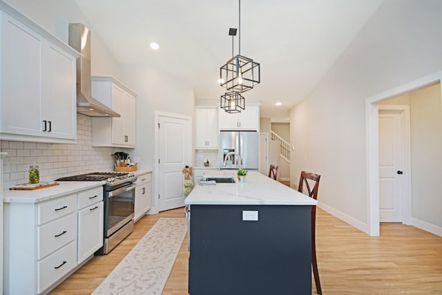 1723 Glenbridge Rd, Bloomington, IL 61704 - kitchen with stainless steel appliances, wall chimney range hood, light wood-style flooring, backsplash, and a kitchen island with sink