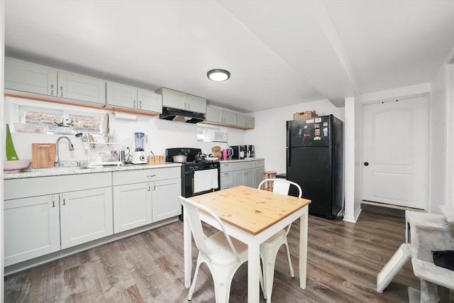 5044 W Roscoe St, Chicago, IL 60641 - kitchen featuring black appliances, under cabinet range hood, wood finished floors, and light countertops