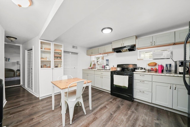 5044 W Roscoe St, Chicago, IL 60641 - kitchen with black gas range, under cabinet range hood, dark wood-style floors, light countertops, and white microwave