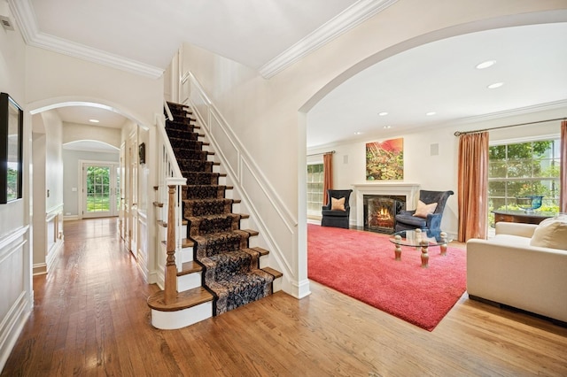 1054 Seneca Rd, Wilmette, IL 60091 - stairs featuring arched walkways, plenty of natural light, a warm lit fireplace, wood finished floors, and ornamental molding