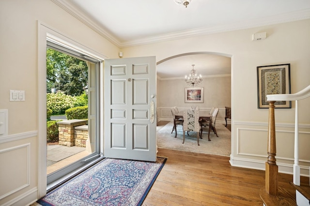 1054 Seneca Rd, Wilmette, IL 60091 - foyer with arched walkways, crown molding, light wood-style flooring, a wainscoted wall, and a chandelier