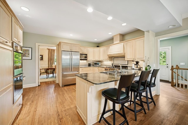 1054 Seneca Rd, Wilmette, IL 60091 - kitchen featuring appliances with stainless steel finishes, light wood-type flooring, dark stone countertops, a kitchen breakfast bar, and recessed lighting