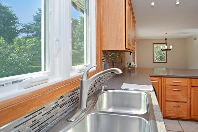 708 Wheeler Dr, Hudson, IL 61748 - kitchen featuring tasteful backsplash, brown cabinetry, decorative light fixtures, and a chandelier