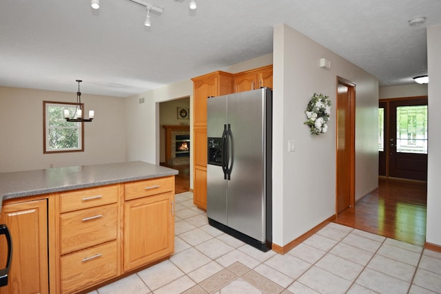 708 Wheeler Dr, Hudson, IL 61748 - kitchen featuring stainless steel fridge with ice dispenser, light tile patterned flooring, a brick fireplace, a chandelier, and pendant lighting
