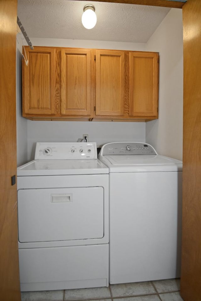 708 Wheeler Dr, Hudson, IL 61748 - washroom featuring washer and clothes dryer, cabinet space, a textured ceiling, and light tile patterned flooring