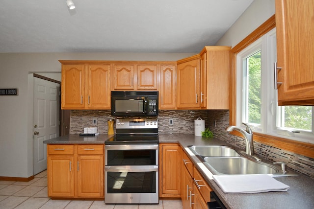 708 Wheeler Dr, Hudson, IL 61748 - kitchen with black microwave, range with two ovens, backsplash, light tile patterned floors, and dark countertops