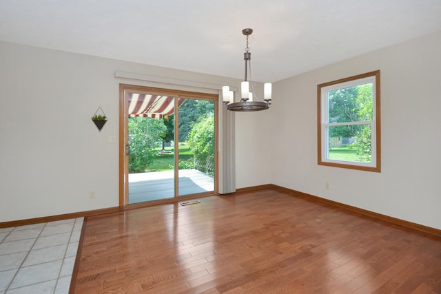 708 Wheeler Dr, Hudson, IL 61748 - empty room with healthy amount of natural light, a chandelier, and light wood-style floors