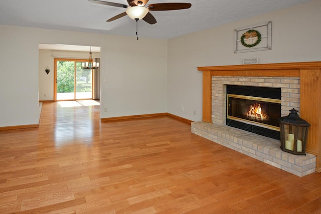 708 Wheeler Dr, Hudson, IL 61748 - unfurnished living room with a ceiling fan, wood finished floors, a fireplace, and a chandelier