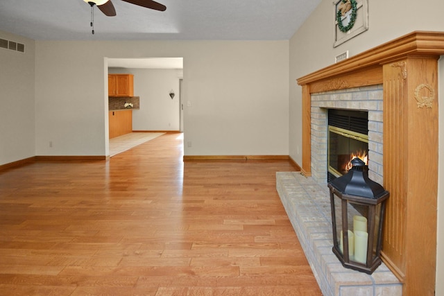 708 Wheeler Dr, Hudson, IL 61748 - unfurnished living room featuring a ceiling fan, light wood-style flooring, and a brick fireplace
