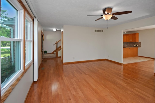 708 Wheeler Dr, Hudson, IL 61748 - empty room with light wood finished floors, stairway, and ceiling fan