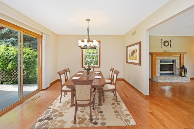 708 Wheeler Dr, Hudson, IL 61748 - dining area with light wood-style floors, a chandelier, and a fireplace