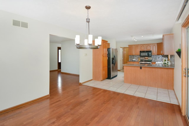 708 Wheeler Dr, Hudson, IL 61748 - kitchen featuring stainless steel appliances, light wood-style flooring, a peninsula, decorative backsplash, and open floor plan