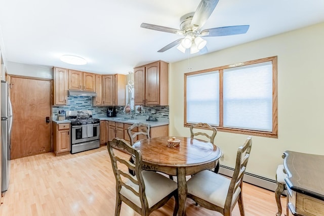2418 S 58th Ave, Cicero, IL 60804 - kitchen with stainless steel appliances, under cabinet range hood, a baseboard heating unit, decorative backsplash, and light wood-style floors