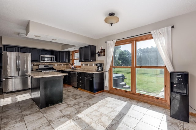 2020 Autumnwood Dr, Ottawa, IL 61350 - kitchen with appliances with stainless steel finishes, dark cabinets, a center island, backsplash, and light tile patterned floors