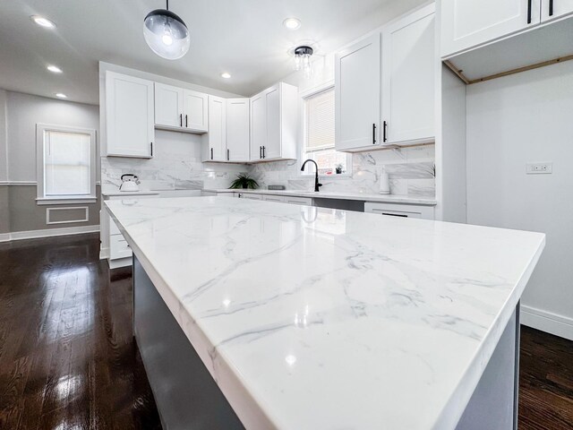 7755 S Wolcott Ave, Chicago, IL 60620 - kitchen with light stone counters, backsplash, dark wood-style flooring, white cabinetry, and decorative light fixtures