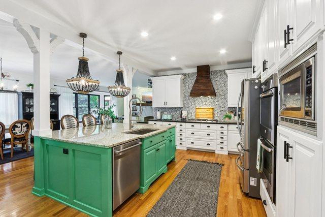 51 Mitchell Cir, Wheaton, IL 60189 - kitchen featuring appliances with stainless steel finishes, white cabinetry, a center island with sink, decorative backsplash, and green cabinets