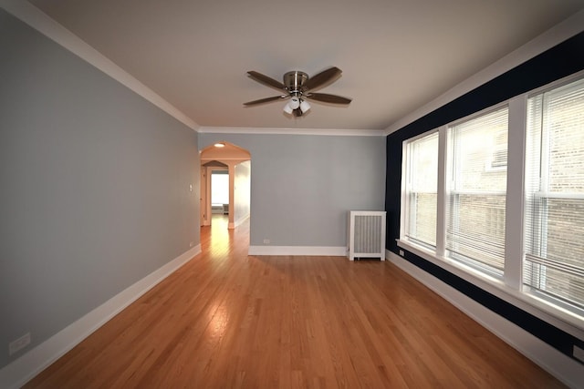 1631 Monroe St, Evanston, IL 60202 - empty room featuring a ceiling fan, arched walkways, crown molding, radiator heating unit, and light wood-style flooring