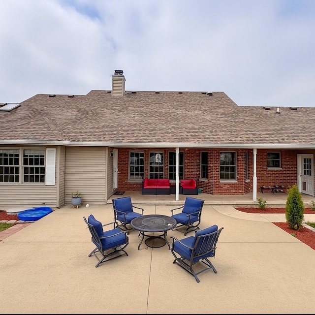 1102 Brian Dr, Manteno, IL 60950 - rear view of house featuring a patio area, an outdoor fire pit, a chimney, brick siding, and a shingled roof