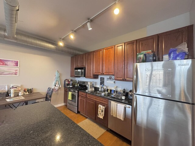 1200 W Monroe St Unit 516, Chicago, IL 60607 - kitchen featuring appliances with stainless steel finishes, dark countertops, light wood-style floors, rail lighting, and brown cabinetry