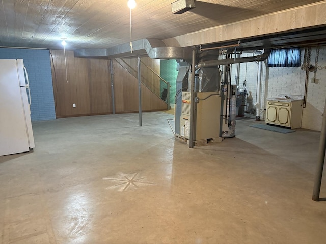 126 N Randolph St, Princeton, IL 61356 - unfinished below grade area featuring freestanding refrigerator, heating unit, brick wall, and water heater