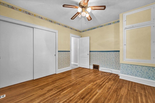 217 S Florence Ave, Bloomington, IL 61701 - unfurnished bedroom with wallpapered walls, wood finished floors, a textured ceiling, a closet, and ceiling fan