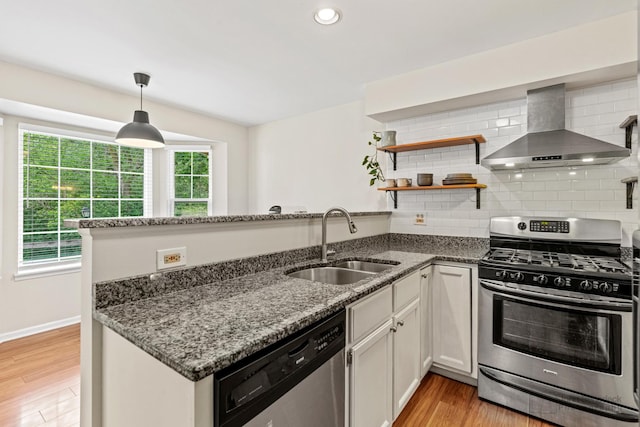 223 New Bridge Ct, Palatine, IL 60067 - kitchen with appliances with stainless steel finishes, wall chimney range hood, a peninsula, dark stone counters, and light wood-style floors