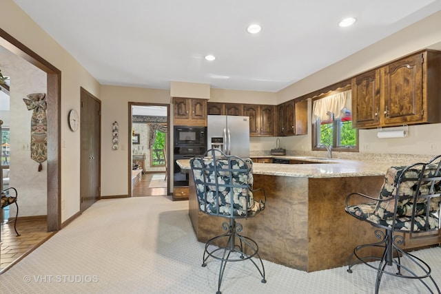 104 Lois Ln, Deer Park, IL 60010 - kitchen with black appliances, a kitchen bar, a peninsula, recessed lighting, and light stone countertops