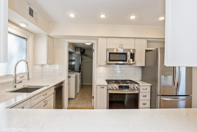 3231 Central St, Evanston, IL 60201 - kitchen with stainless steel appliances, separate washer and dryer, decorative backsplash, white cabinets, and recessed lighting