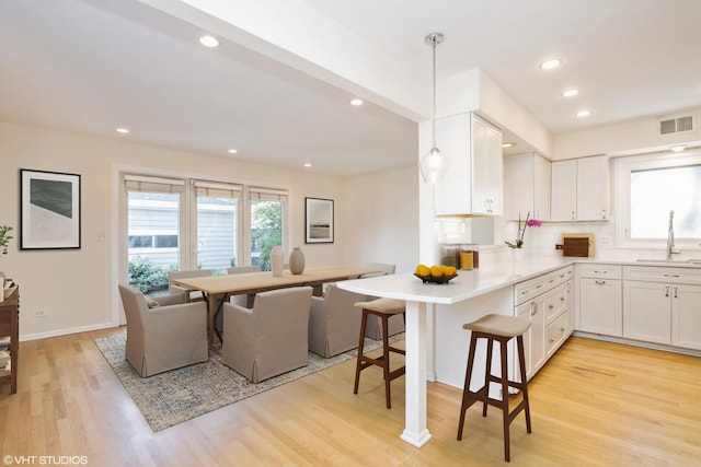 3231 Central St, Evanston, IL 60201 - kitchen featuring white cabinets, light wood-style flooring, a peninsula, tasteful backsplash, and recessed lighting