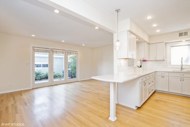 3231 Central St, Evanston, IL 60201 - kitchen featuring white cabinets, light wood finished floors, tasteful backsplash, recessed lighting, and a peninsula