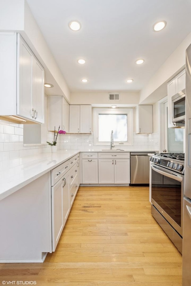 3231 Central St, Evanston, IL 60201 - kitchen with stainless steel appliances, white cabinetry, backsplash, and recessed lighting